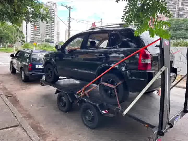 SUV escuro preso por cintas sobre o reboque-plataforma da MJC